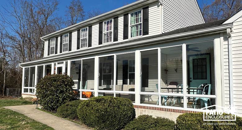 : Image of a white colonial home with glass-enclosed full front porch.