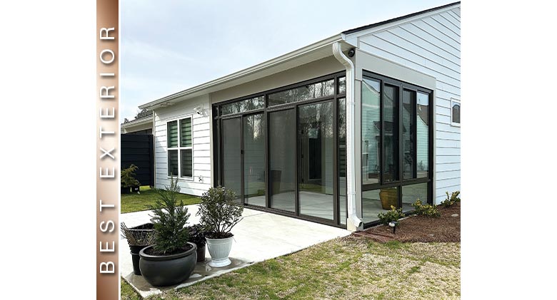 BEST EXTERIOR: Brown corner patio enclosure with transom and glass knee wall on side, potted plants on patio in front.