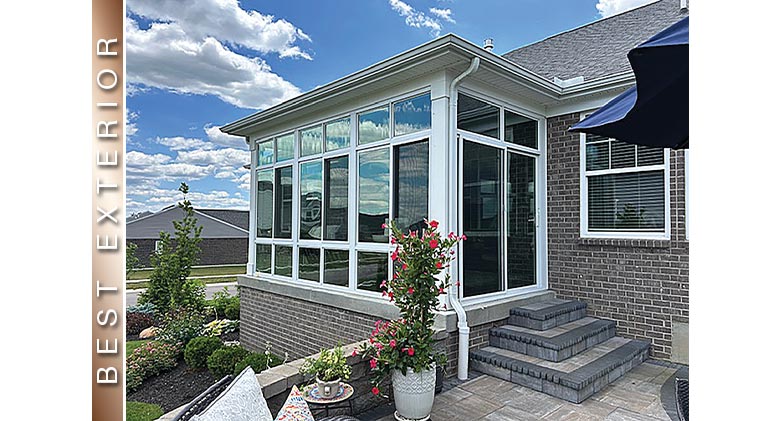 BEST EXTERIOR: White patio enclosure w/glass knee wall & patio doors on side with 3 steps leading to patio w/potted plants.