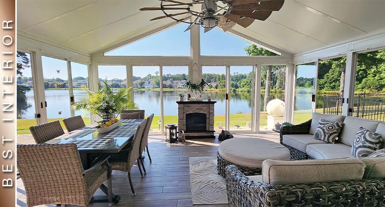 BEST INTERIOR: An expansive view of lake from interior of white sunroom with dining area, seating area, fireplace, ceiling fan.