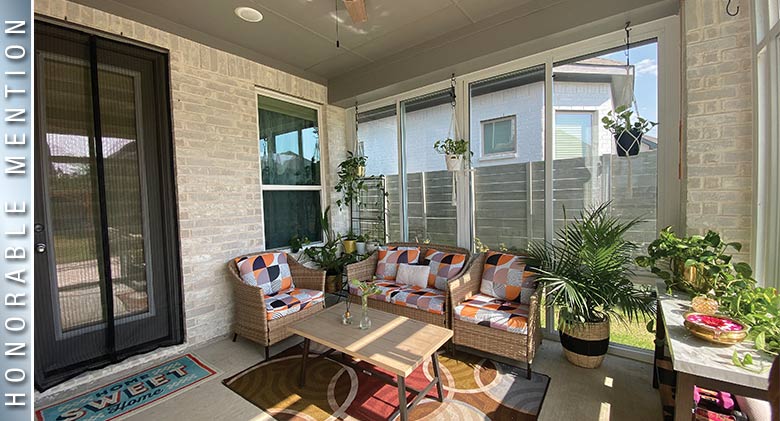 HONORABLE MENTION: Interior of patio enclosure with tan wicker furniture with bright cushions, coffee table, and plants.