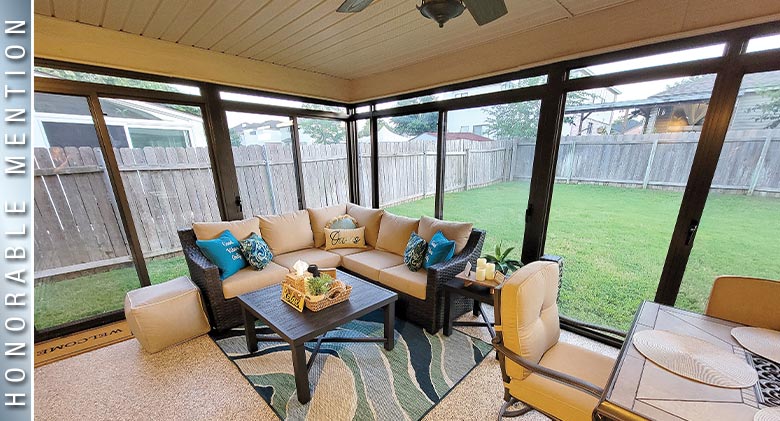 HONORABLE MENTION: Corner sofa in beige with blue pillows, coffee table, and dining table in brown sunroom. Backyard view.