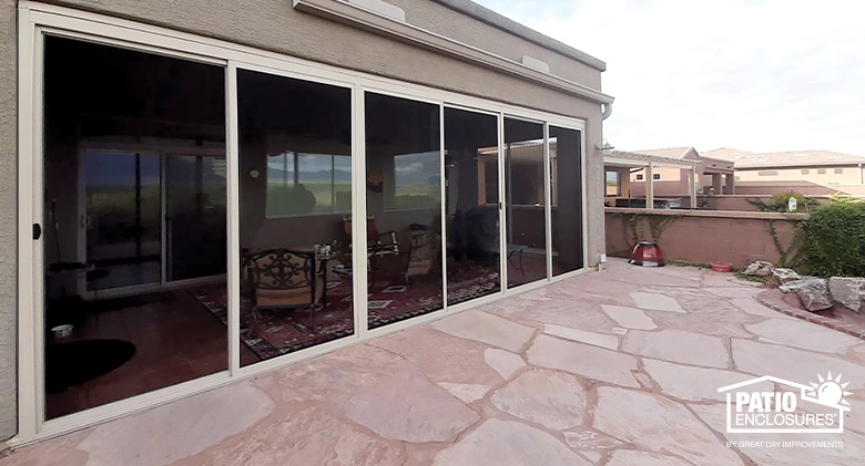 A pink stone patio with irregular shapes, partially enclose with a screen room.