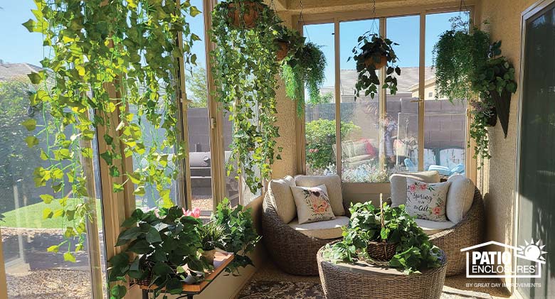 Small sunroom with beige walls, two cozy chairs in beige, a coffee table and several plants