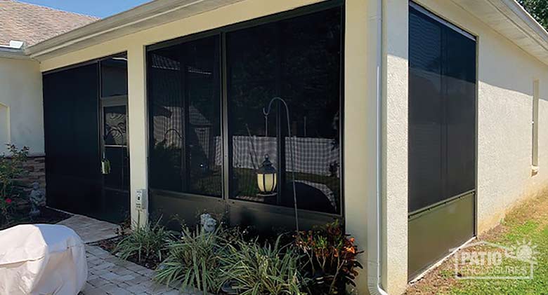  The exterior of a sunroom with a solid knee wall in dark brown and a small garden in front.