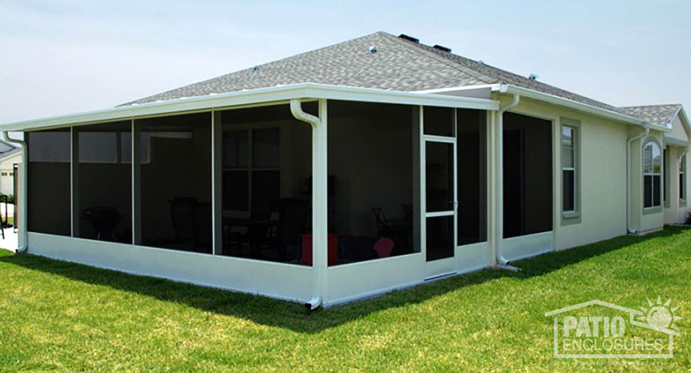 An exterior view of a white screen room with kickplate on a beige stucco house.