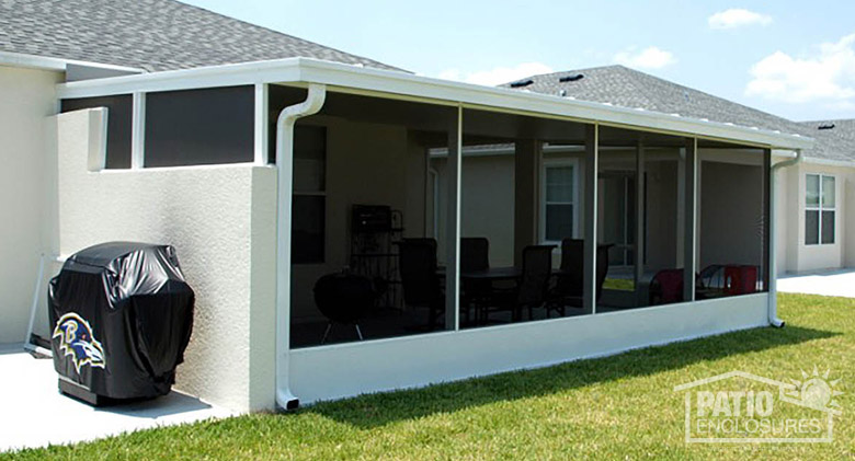 A covered grill outside a white screen room patio enclosure with aluminum kickplate.