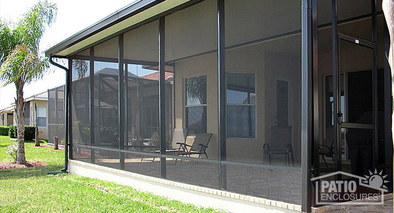 A brown screen room patio enclosure with screen door and solid, insulted roof.