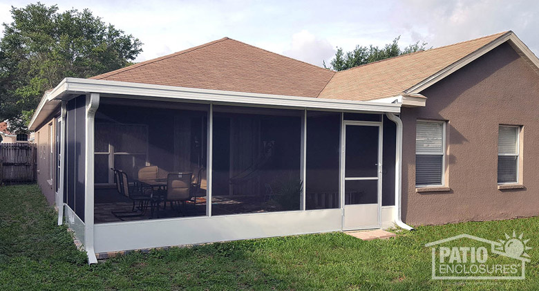 A brown screen room patio enclosure with a screened roof on half and an insulated roof on the other half.