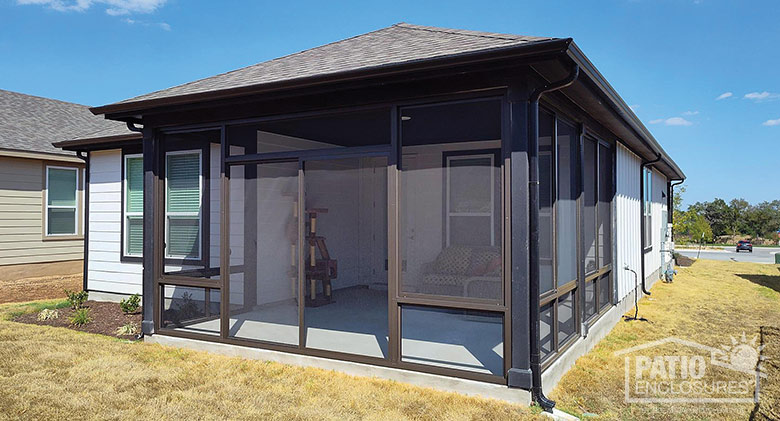 Looking into a brown screen room with hip roof; a cat tree and loveseat can be seen.