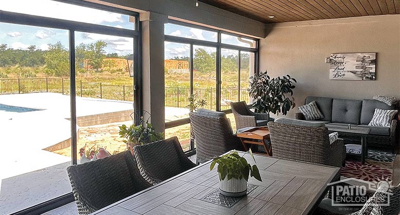 A dining table and chairs as well as a comfortable seating area in a shady screened-in lanai or porch.