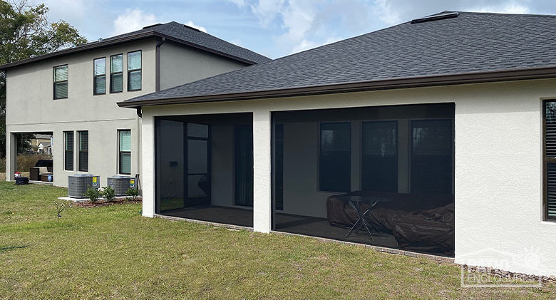 A wide corner lanai or porch enclosed with almost see-through screening.