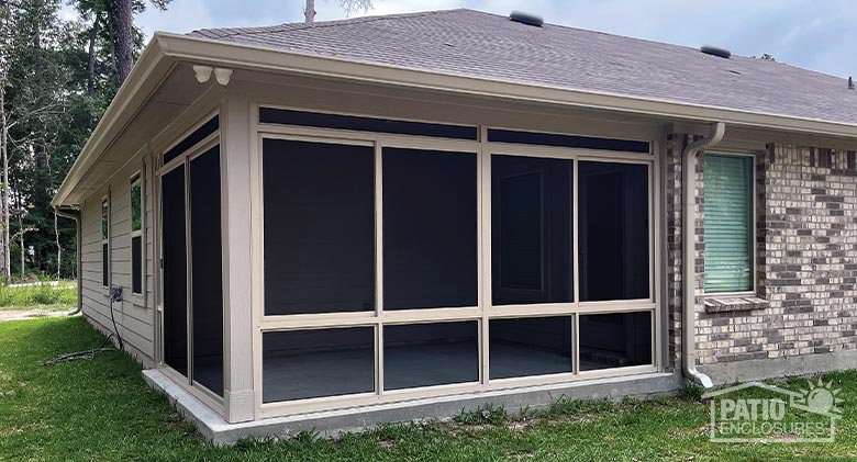 A porch or lanai screen enclosure on the corner of a brick home.