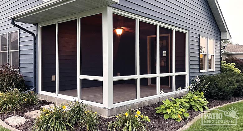 A corner porch or lanai screen enclosure with neat flower beds all around.