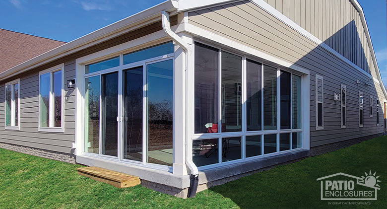 A corner porch or lanai enclosure with a white frame, glass knee wall, and sliding doors.